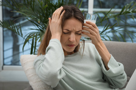 Woman holding glass of medicine for hangover at homeの写真素材