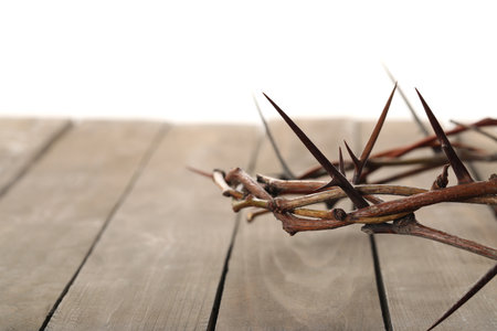 Crown of thorns on wooden table against white background, closeup with space for text. Easter attributeの写真素材