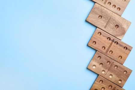 Wooden domino tiles on light blue background, flat lay. Space for textの写真素材