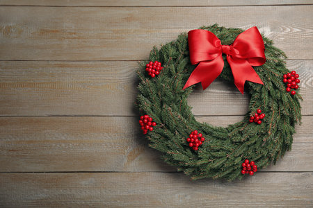Beautiful Christmas wreath with red berries and bow on wooden background. Space for textの写真素材