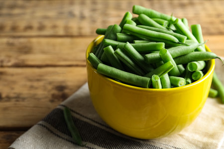Fresh green beans in bowl on wooden table, closeup. Space for textの写真素材
