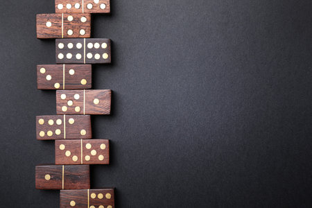 Wooden domino tiles on black background, flat lay. Space for textの写真素材
