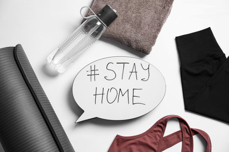 Stylish sportswear, yoga mat and speech bubble with hashtag Stay at Home on white background, flat lay.の写真素材