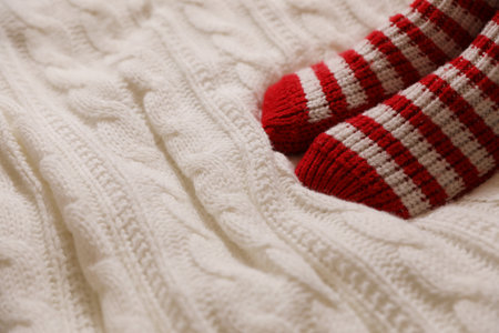 Woman in warm socks on knitted blanket, closeup. Space for textの写真素材