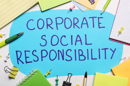 Paper text balloon with phrase Corporate Social Responsibility among office supplies on white table, flat layの写真素材