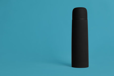 Stylish thermo bottle on light blue background, space for textの写真素材