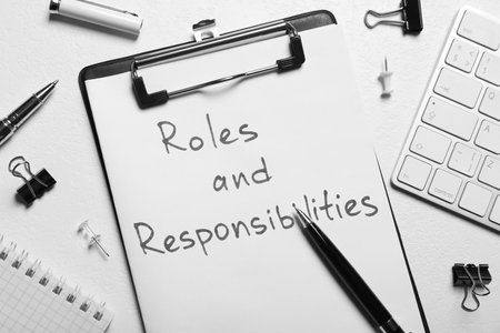 Clipboard with sheet of paper saying Roles and Responsibilities among office supplies on white table, flat layの写真素材