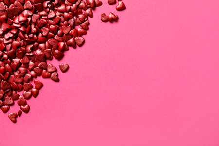 Red heart shaped sprinkles on pink background, flat lay. Space for text