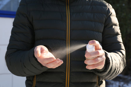Man spraying antiseptic onto hand outdoors, closeupの写真素材