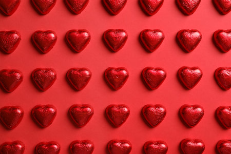 Tasty chocolate heart shaped candies on red background, flat layの写真素材