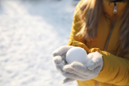 Woman holding snowball outdoors on winter day, closeup. Space for textの写真素材