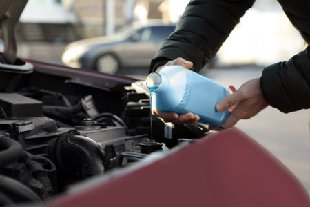 Man filling car radiator with antifreeze outdoors, closeupの写真素材