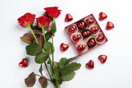 Heart shaped chocolate candies and bouquet on white background, top viewの写真素材