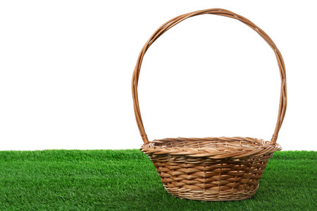Empty wicker basket on green lawn against white background. Space for design. Easter itemの写真素材