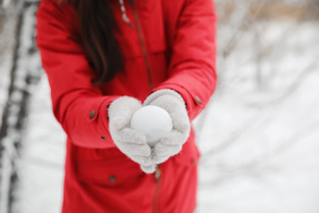 Young woman holding snowball outdoors on winter day, closeupの写真素材