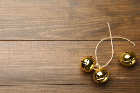 Golden sleigh bells with rope on wooden background, flat lay. Space for textの写真素材