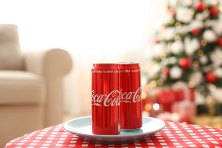 MYKOLAIV, UKRAINE - JANUARY 15, 2021: Coca-Cola cans on table in room with Christmas treeのeditorial素材