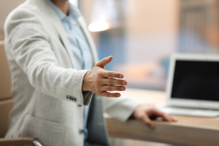 Businessman offering handshake in office, closeup. Space for textの写真素材