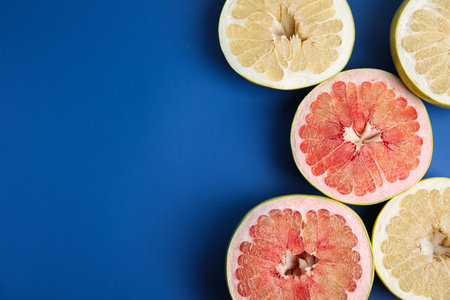 Fresh cut pomelo fruits on blue background, flat lay. Space for textの写真素材