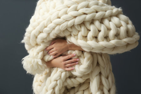 Woman holding soft knitted blanket on gray background, closeupの写真素材