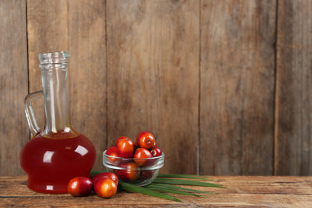 Palm oil in glass jug, tropical leaf and fruits on wooden table. Space for textの写真素材