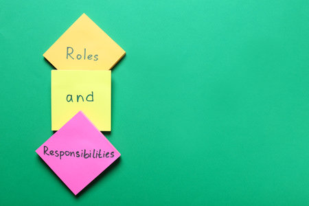 Sticky notes with words phrase forming Roles And Responsibilities on green background, flat lay. Space for textの写真素材