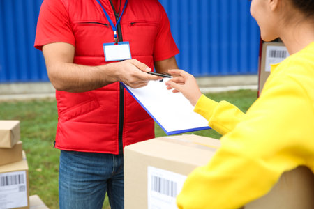 Courier receiving receipt signature from customer outdoors, closeupの写真素材