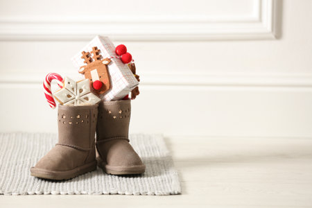 Sweets and gift box in child's boots indoors, space for text. St. Nicholas Day Traditionの写真素材