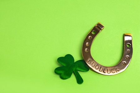 Golden horseshoe and decorative clover leaf on light green background, space for text. Saint Patrick's Day celebrationの写真素材