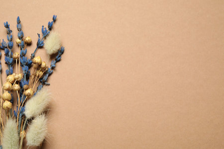 Bouquet of dried flowers on light brown background, flat lay. Space for textの写真素材