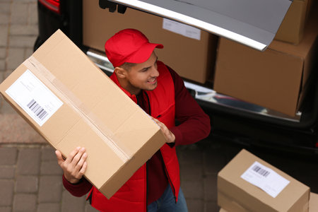 Courier with parcel near delivery van outdoors, above viewの写真素材
