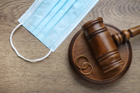 Gavel, protective mask and wedding rings on wooden table, flat lay. Divorce during coronavirus quarantineの写真素材