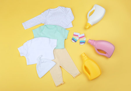 Flat lay composition with detergents and children's clothes on yellow backgroundの写真素材