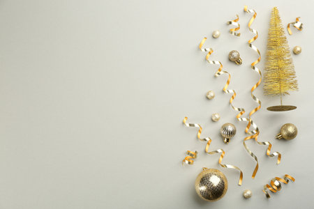 Shiny serpentine streamers, Christmas balls and decorative tree on light gray background, flat lay. Space for textの写真素材