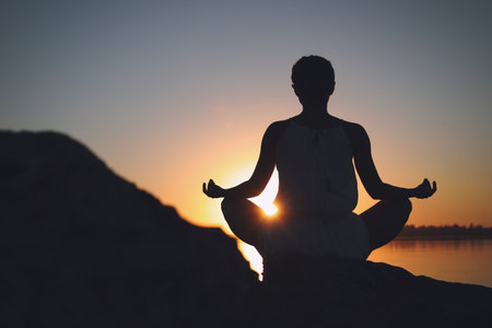 Woman practicing yoga near river on sunset. Healing conceptの写真素材
