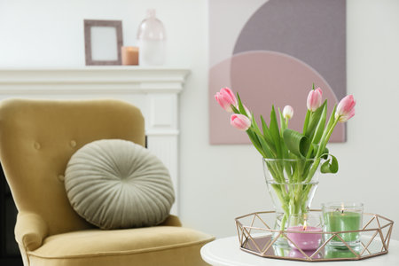 Beautiful tulips and burning candles on white table indoors, space for text. interior designの写真素材