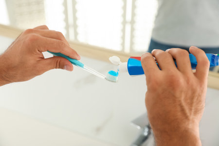 Man applying toothpaste on brush in bathroom, closeupの写真素材