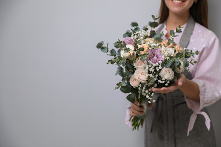 Florist holding beautiful wedding bouquet on light gray background, closeup. Space for textの写真素材