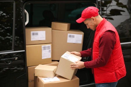 Courier with parcels near delivery van outdoorsの写真素材