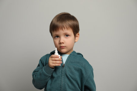 Little boy with nasal spray on light gray backgroundの写真素材