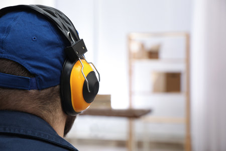 Worker wearing safety headphones indoors, closeup. Hearing protection deviceの写真素材