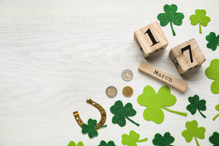 Flat lay composition with block calendar on white wooden table, space for text. Saint Patrick's Day...