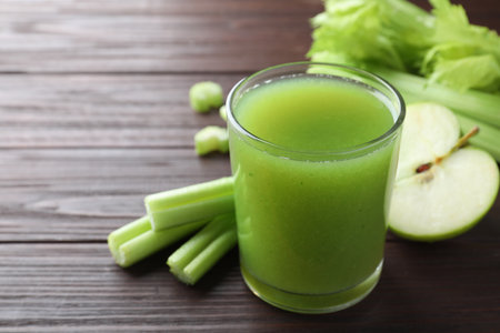 Glass of celery juice and fresh ingredients on wooden table, closeupの写真素材