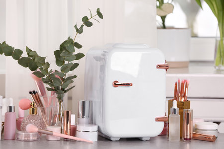 White mini cosmetics refrigerator and skin care products on tableの写真素材