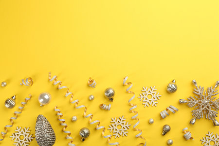 Flat lay composition with serpentine streamers and Christmas decor on yellow background. Space for textの写真素材