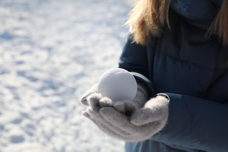 Woman holding snowball outdoors on winter day, closeup. Space for textの写真素材
