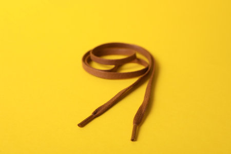 Long brown shoe lace on yellow backgroundの写真素材