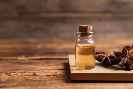 Bottle of essential oil and anise on wooden table. Space for textの写真素材
