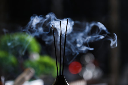 Incense sticks smoldering in holder on blurred background, closeupの写真素材