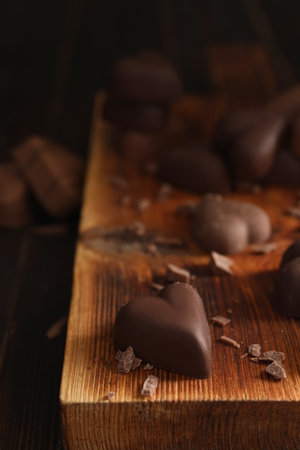 Beautiful heart shaped chocolate candies on wooden board, closeup with space for textの写真素材